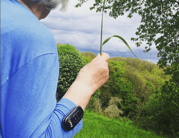 Personne âgée tient une fleur dans la main avec un traceur GPS de PAJ autour du bras
