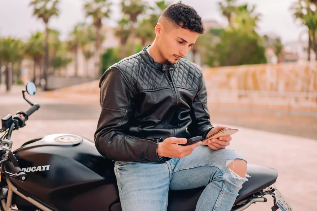 Un homme tien un traceur GPS de PAJ dans la main comme mesure de protection antivol pour moto