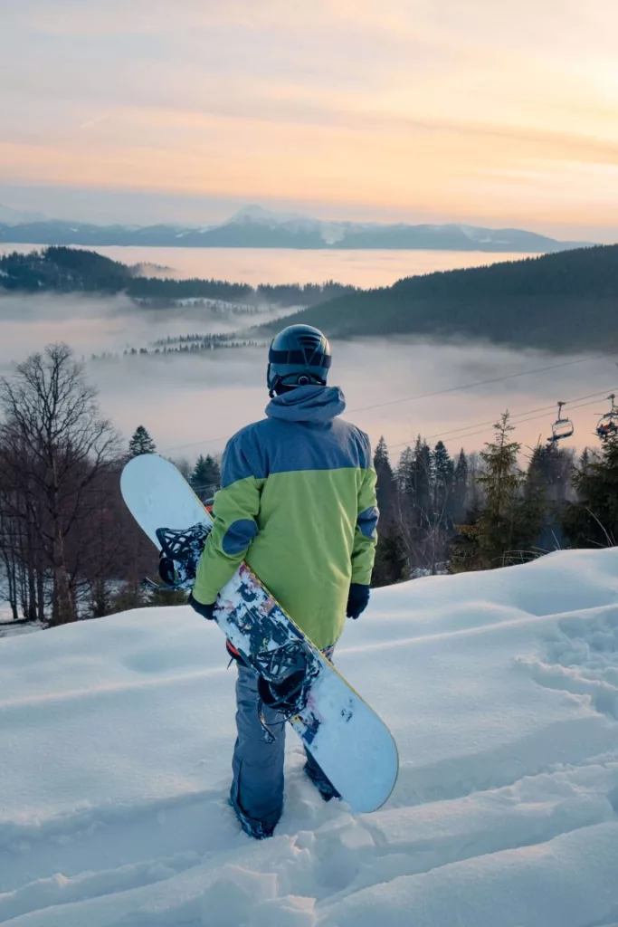 Un snowboardeur profit de la vue sur la montagne enneigees au coucher du soleil
