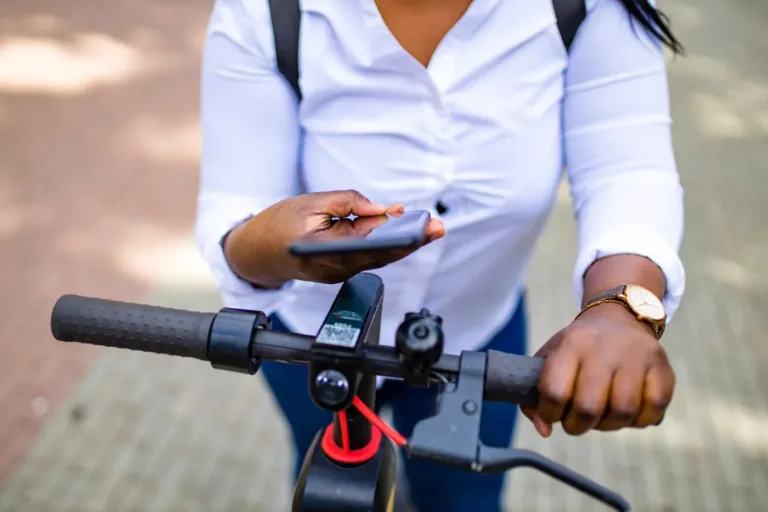 Une femme afro-americaine sur son E-bike equipe d un dispositif antivol velo gps avec un telephone en main