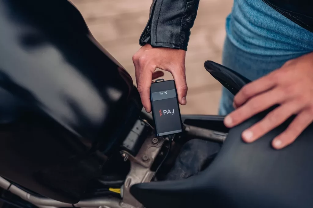 Un homme installe un traceur GPS à connexion fixe sur sa moto pour bien le cacher
