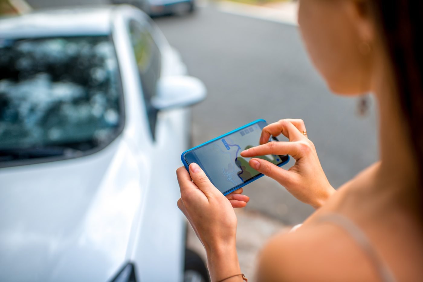 Une femme utilise lapplication de PAJ GPS de son telephone devant une voiture