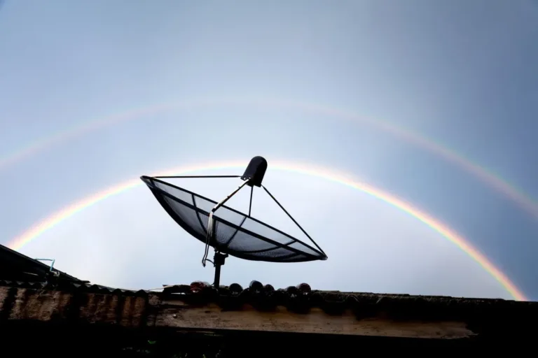 Une antenne satelite sur le toit avec arcanciel en arriere plan