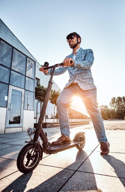 Un homme en costume elegant utilise son E-scooter