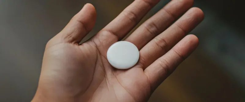 Une main tenant l'AirTag de Apple