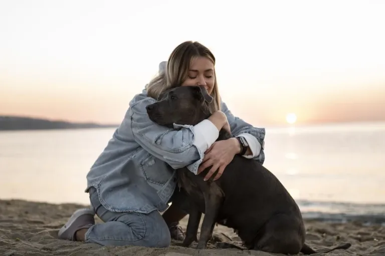 Une jeune femme prend son chien dans ses bras sur une plage